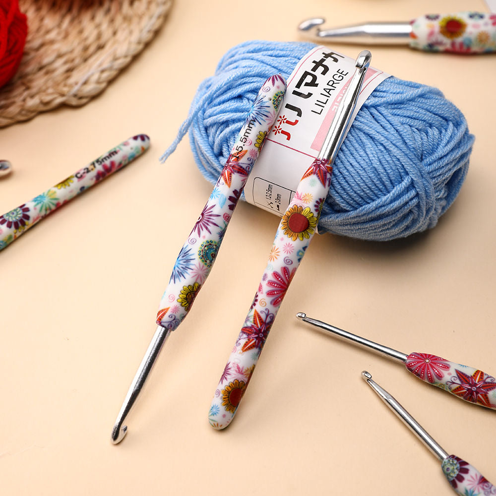 Ball of blue yarn with floral-handled crochet hooks on a beige surface